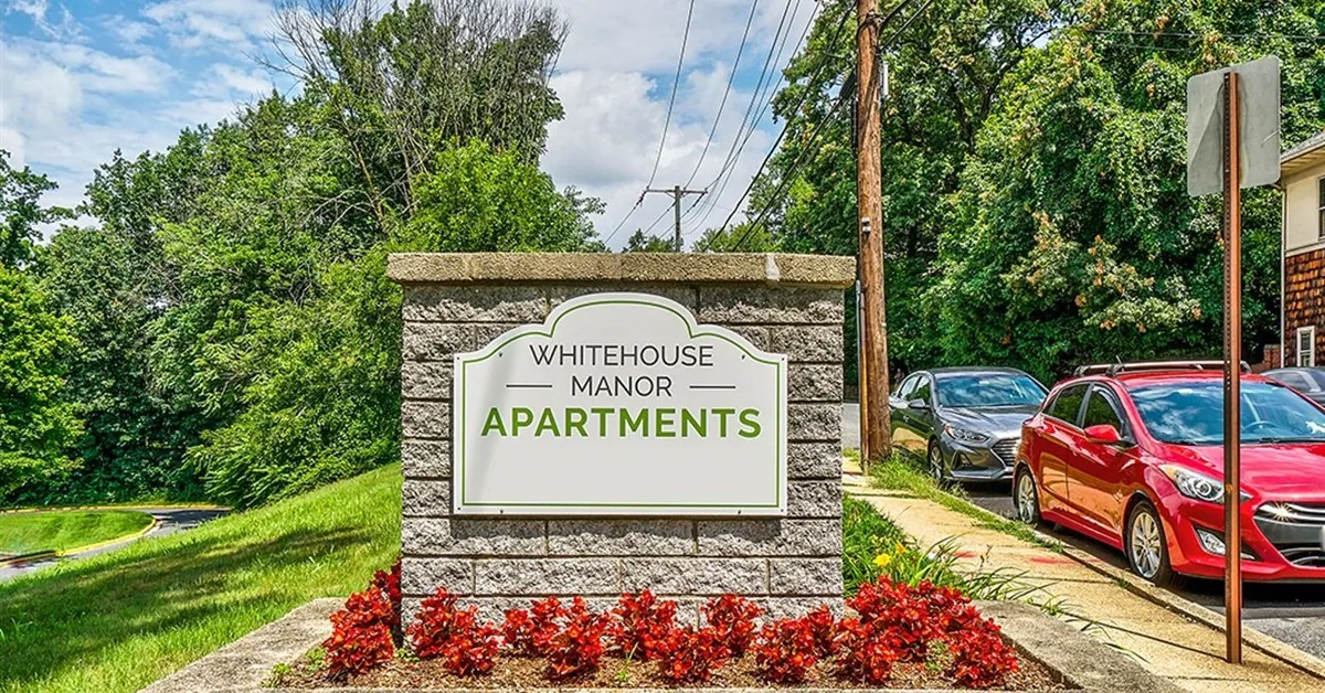 Whitehouse Manor Apartments stone entrance sign with red flowers